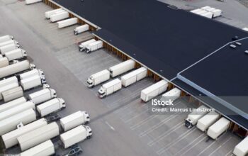 Aerial view of a large distribution warehouse loading dock with many trucks outside.